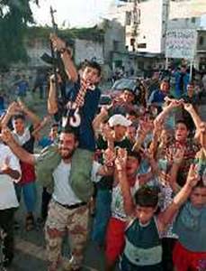 A Palestinian boy fires an assault rifle in celebration as children dance at the Ain al-Hilweh refugee camp near the port city Sidon in south Lebanon September 11, 2001.